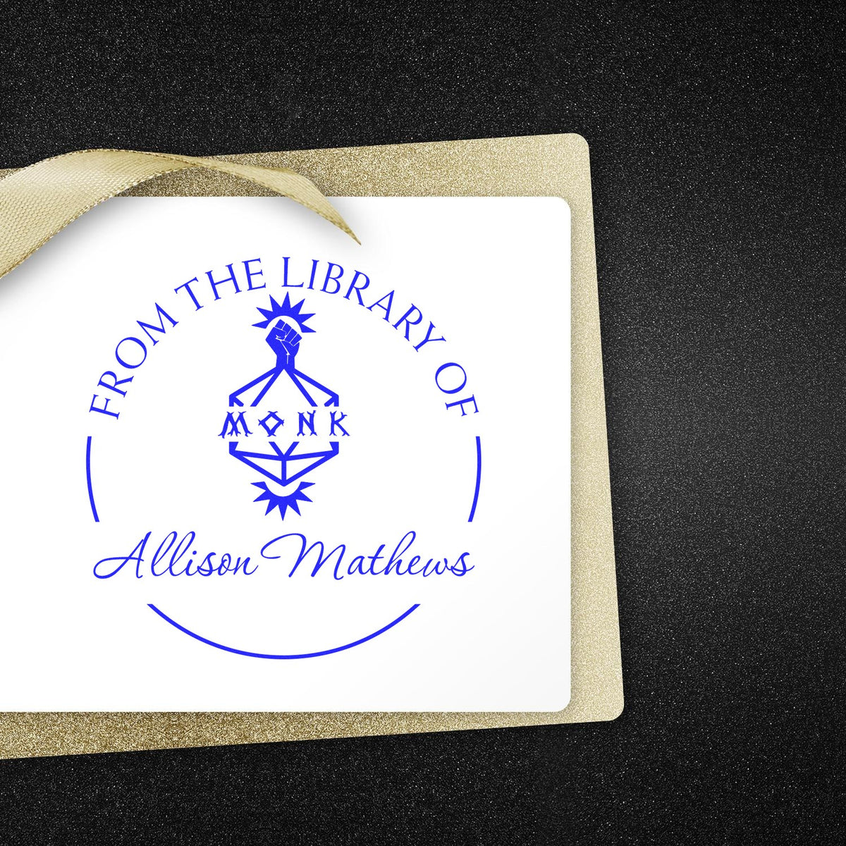 Blue custom library stamp seal on white card with gold glitter border and ribbon, reading From the Library of Allison Mathews.