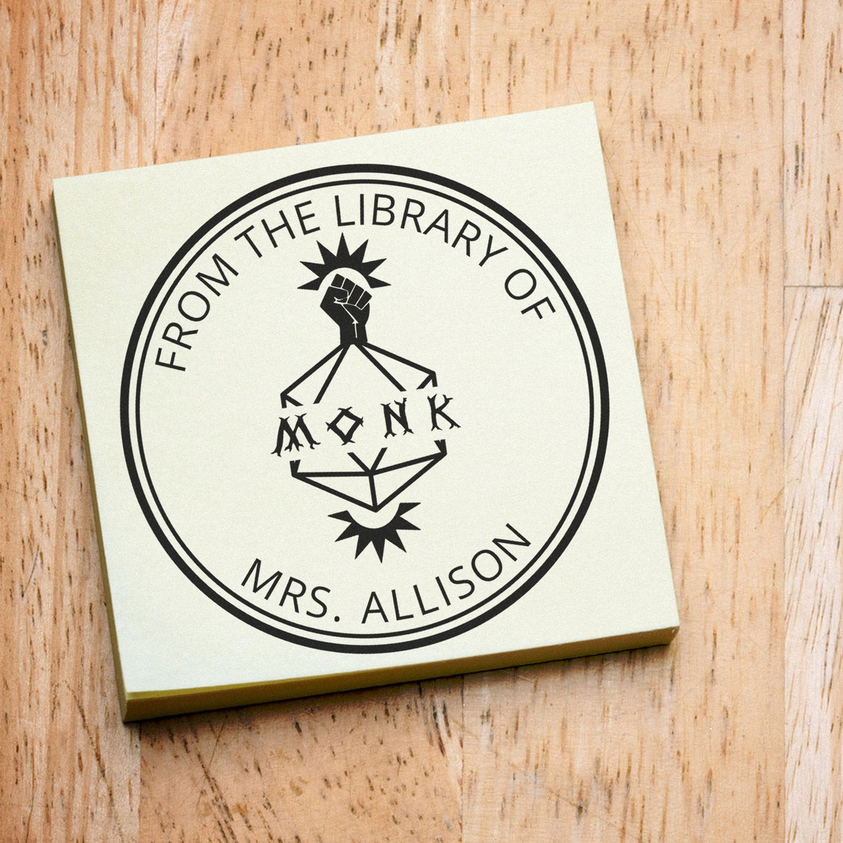 Cream custom library stamp seal with black circular "From the Library of Mrs. Allison" design on light wood.