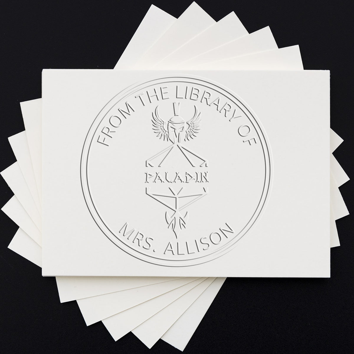 White embossed stamp and seal cards with a circular library seal design on a black background.