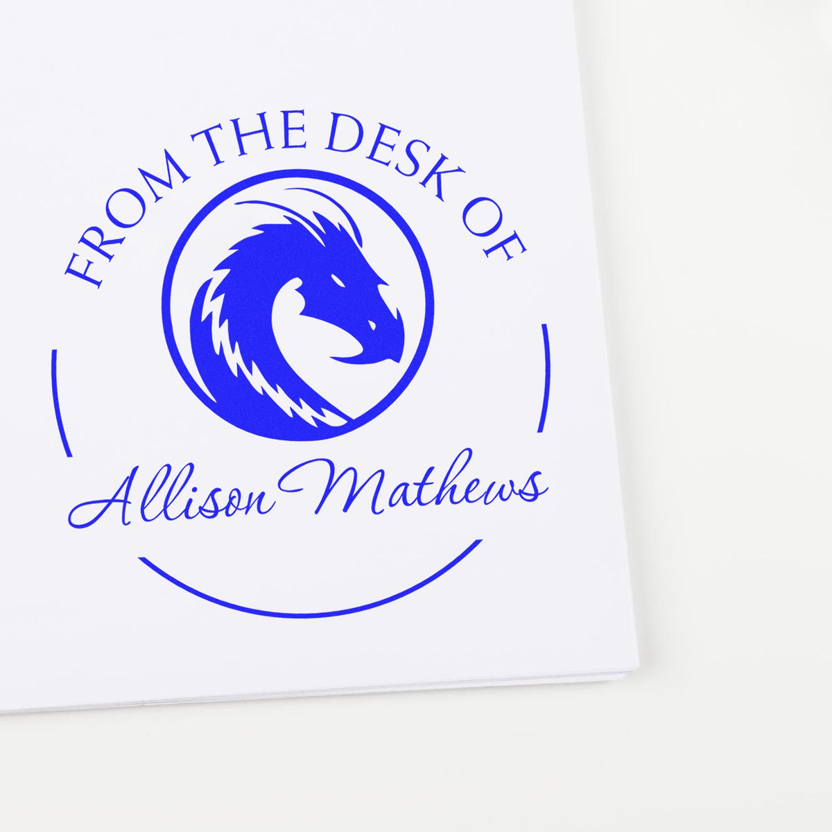 Blue circular custom desk stamp seal with dragon logo and Allison Mathews text on white paper