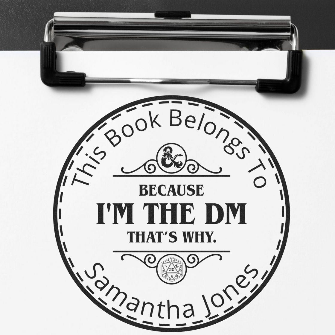 Black circular book stamp and seal on white paper, reading This Book Belongs To Samantha Jones and Because Im the DM.