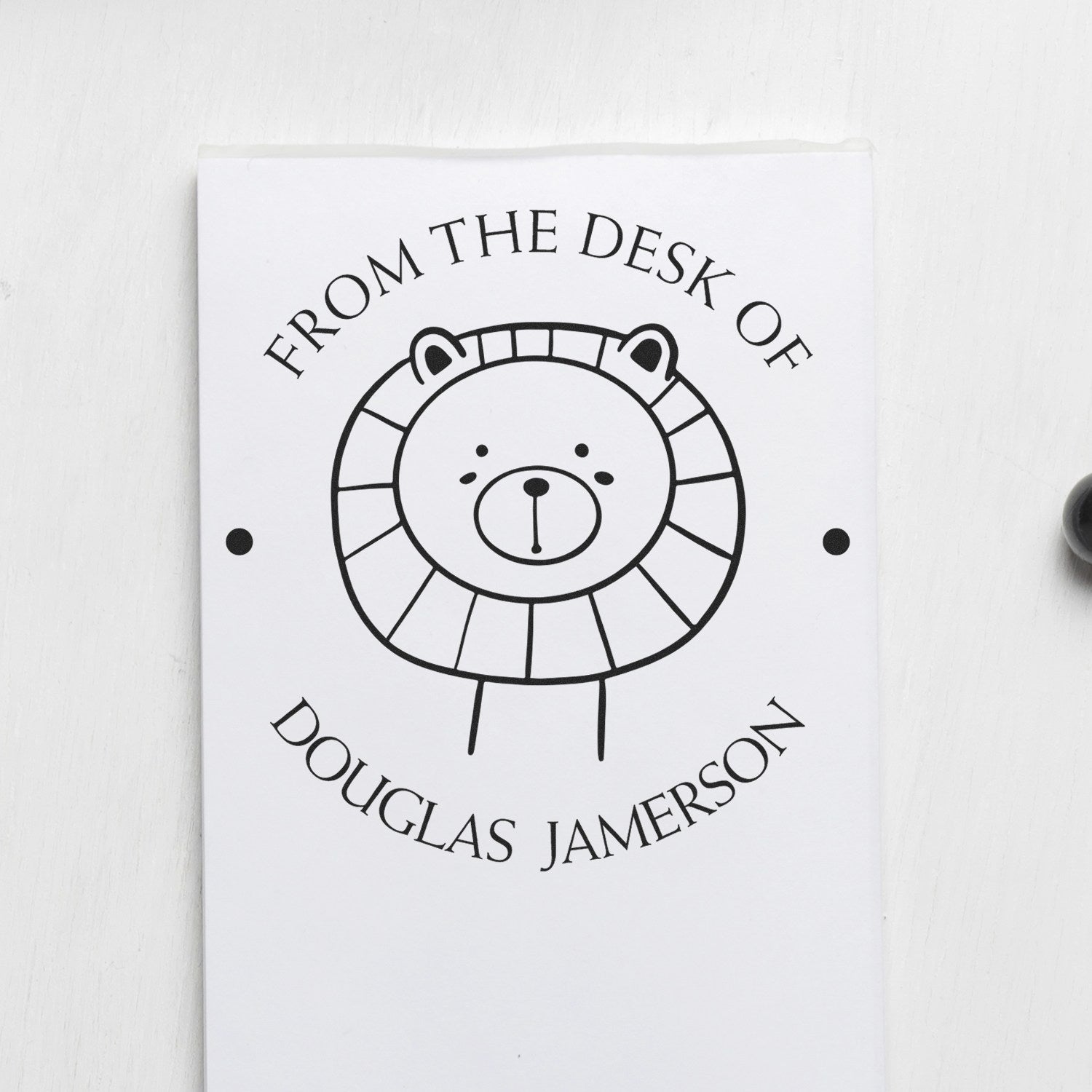 A personalized home stamper with a wood handle features a FlutterPaws cartoon animal design. The stamp displays From the desk of Douglas Jamerson with a cute lion illustration, ideal for a personalized book mark stamp.
