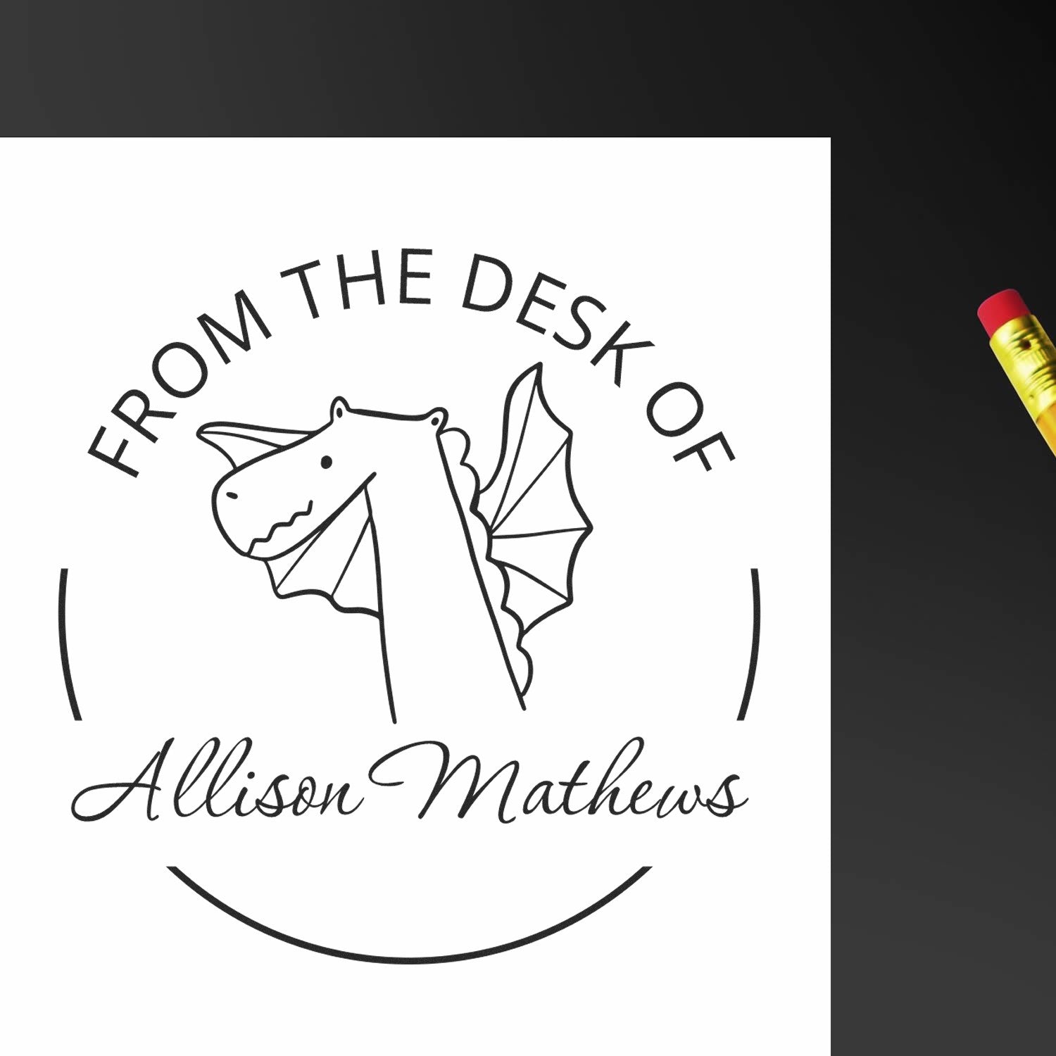 Image of a paper stamped with a cartoon dragon and the text "From the Desk of Allison Mathews." A pencil is nearby. Keywords: Wood Handle SnuggleSnout Cartoon Animal Personalized Library Book Belongs To Stamp, Customized New Address Stamper.