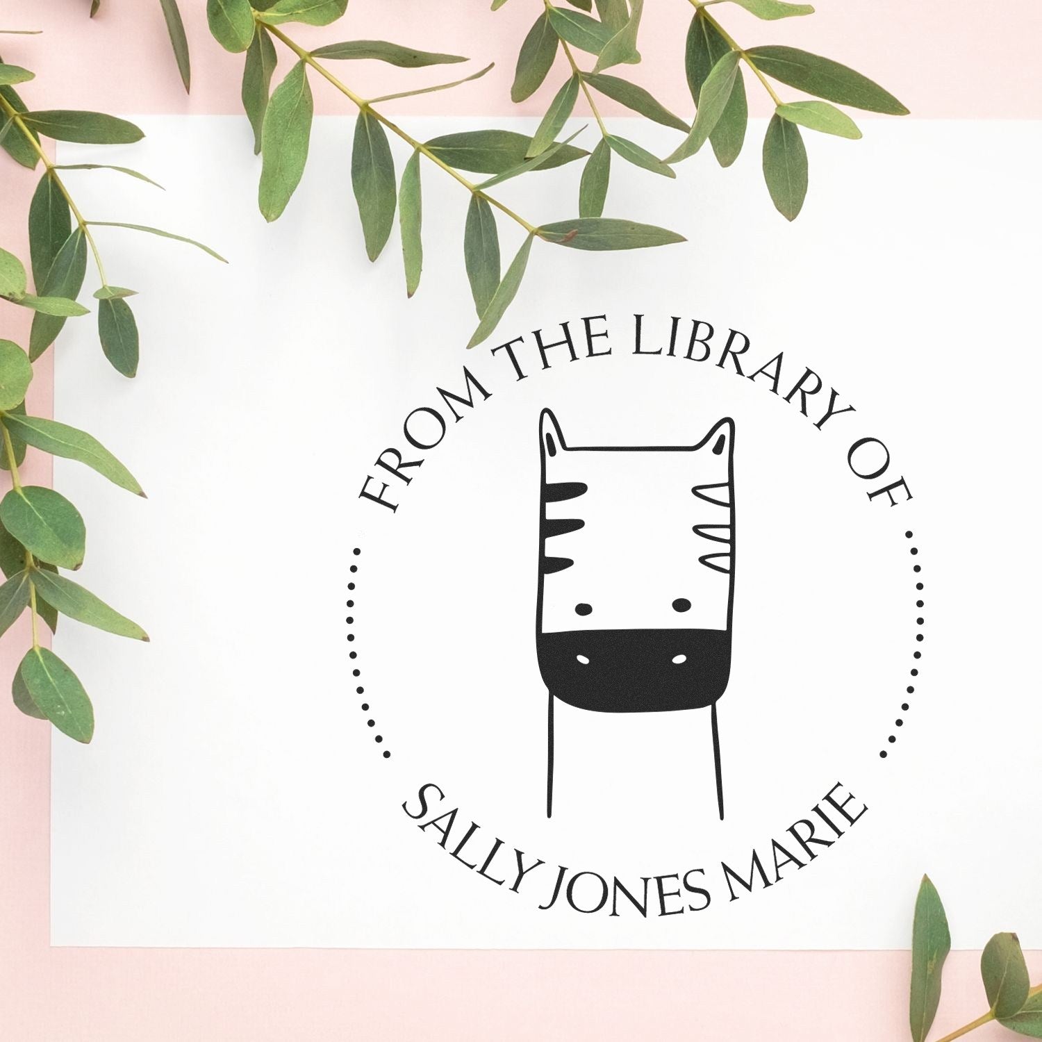 Cartoon animal self-inking custom-made stamp from PuzzlePounce, featuring a cute zebra design with the text "From The Library Of" and "Sally Jones Marie." Surrounded by green leaves, this custom return mail stamper adds a personal touch.