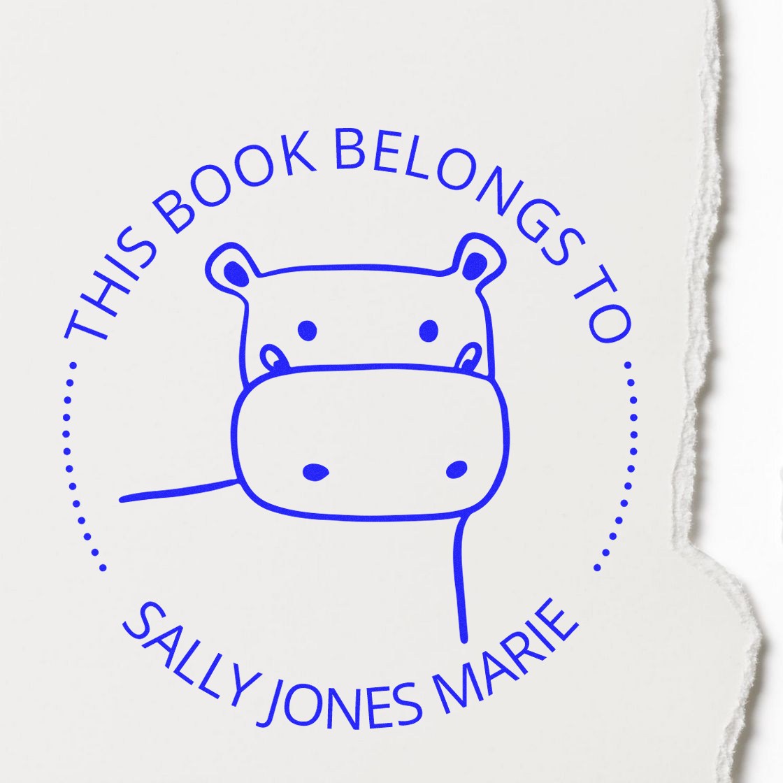A Wood Handle TizzyTwitch Cartoon Animal Customized Book Stamp featuring a hippo design and the text This Book Belongs To Sally Jones Marie. The stamp is used as a Custom Home Stamp on a torn paper background.