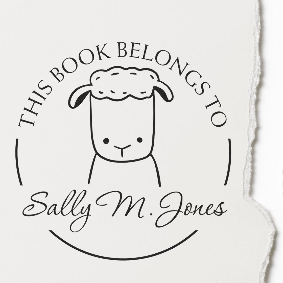 A stamp impression on paper featuring a cartoon animal with a woolly head, labeled This Book Belongs To Sally M. Jones. The design is a Wood Handle TwirlTail Cartoon Animal Customized From The Library Of Stamp, ideal for a Custom-Made New Address Stamp.
