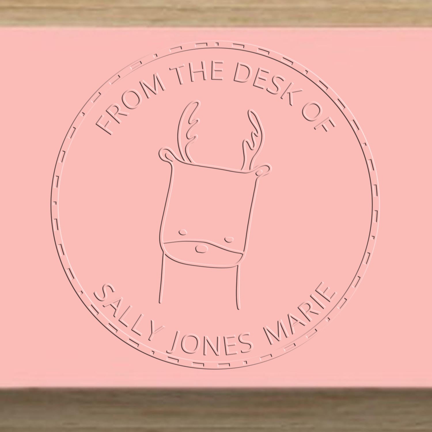 Image of a MerryMuzzle cartoon animal embossing seal on pink paper, featuring antlers and the text "From the Desk of Sally Jones Marie." The seal is part of a personalized library collection. A personalized new address stamper is also visible.