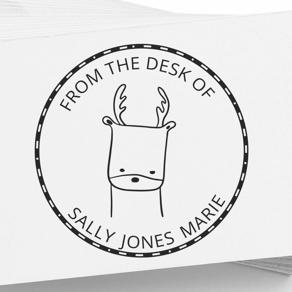 Image of a custom-made library stamp featuring a cartoon animal with antlers, labeled "From the Desk of Sally Jones Marie." The stamp has a wood handle and is part of the MerryMuzzle collection. It also serves as a new address stamper.