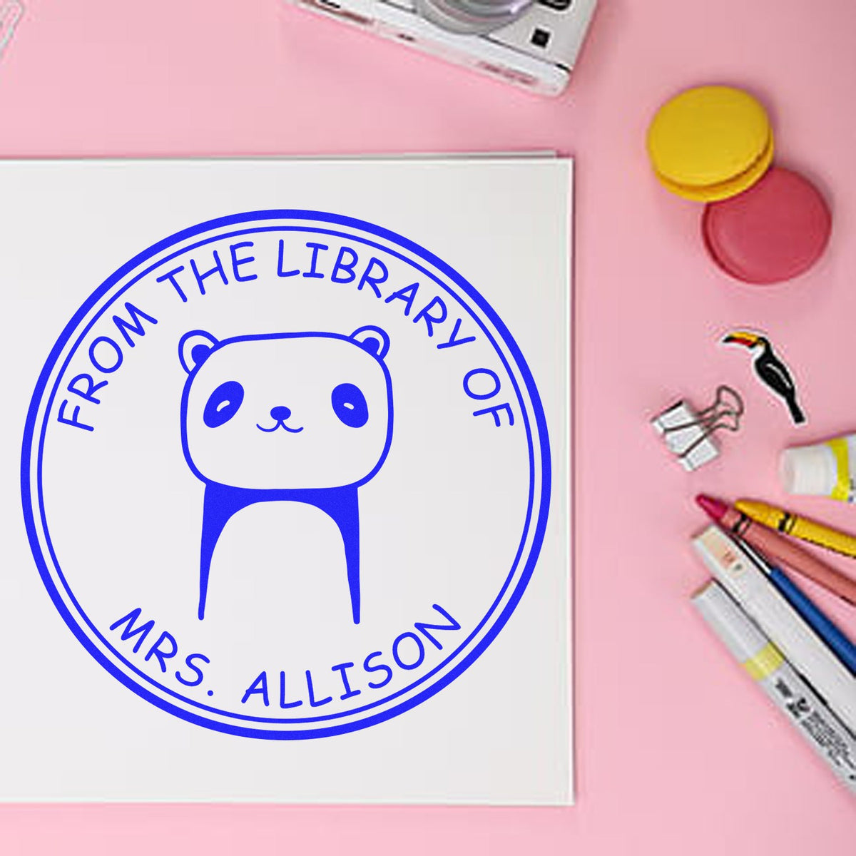 Slim Pre-Inked TumbleTuft Cartoon Animal Custom Library Gift Stamp featuring a cute animal design with "From the Library of Mrs. Allison" text. Personalizable Address Stamp option available. Surrounded by stationery on a pink background.