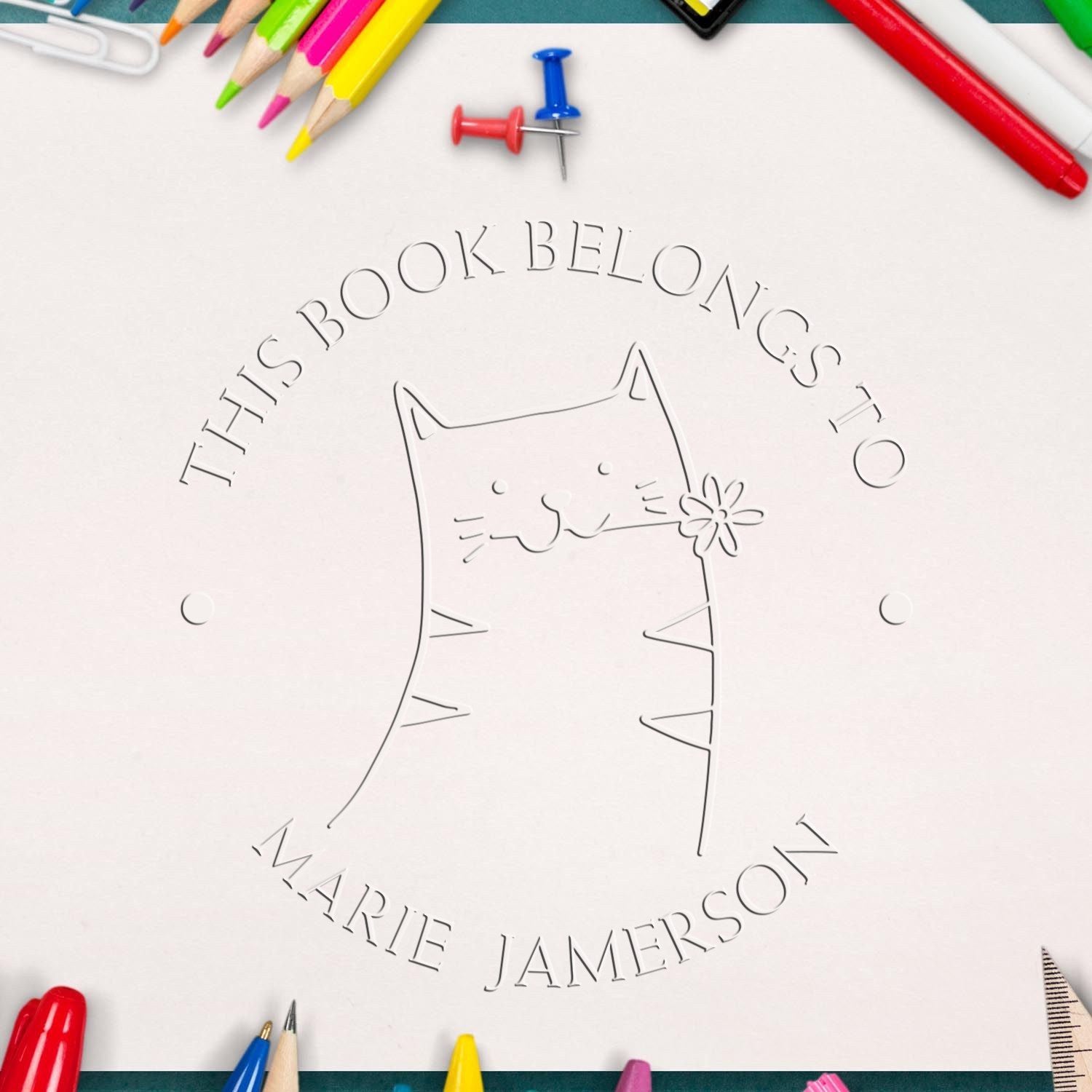 Soft HuddleHopper cartoon animal design embossed on a custom-made book personalization embosser. The image shows a playful cat with a flower, surrounded by colorful stationery, highlighting a custom home stamper for personalized book ownership.
