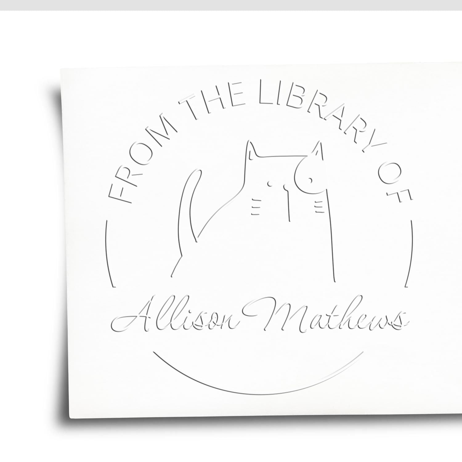 Image of a GobbleGiggle Cartoon Animal Desk Personalizable Bookplate Embosser featuring a cat design with the text "From the Library of Allison Mathews." This Custom-Made Address Stamper is embossed on white paper, showcasing a playful and personalized touch.