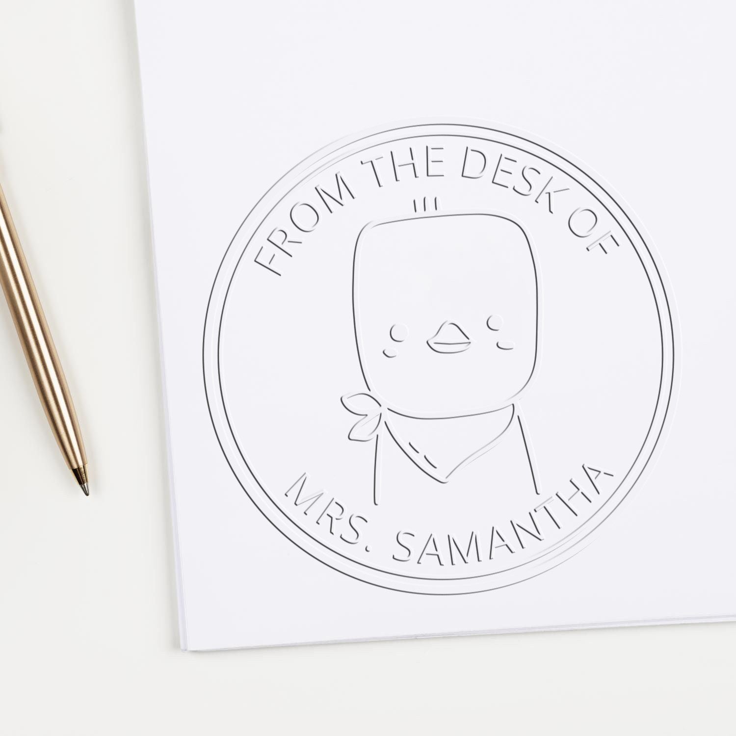 A Soft PuddlePaddle cartoon animal is embossed on a white sheet using a custom-made book property embosser. The design features a customizable mailing stamp with the text "From the Desk of Mrs. Samantha" surrounding the character.