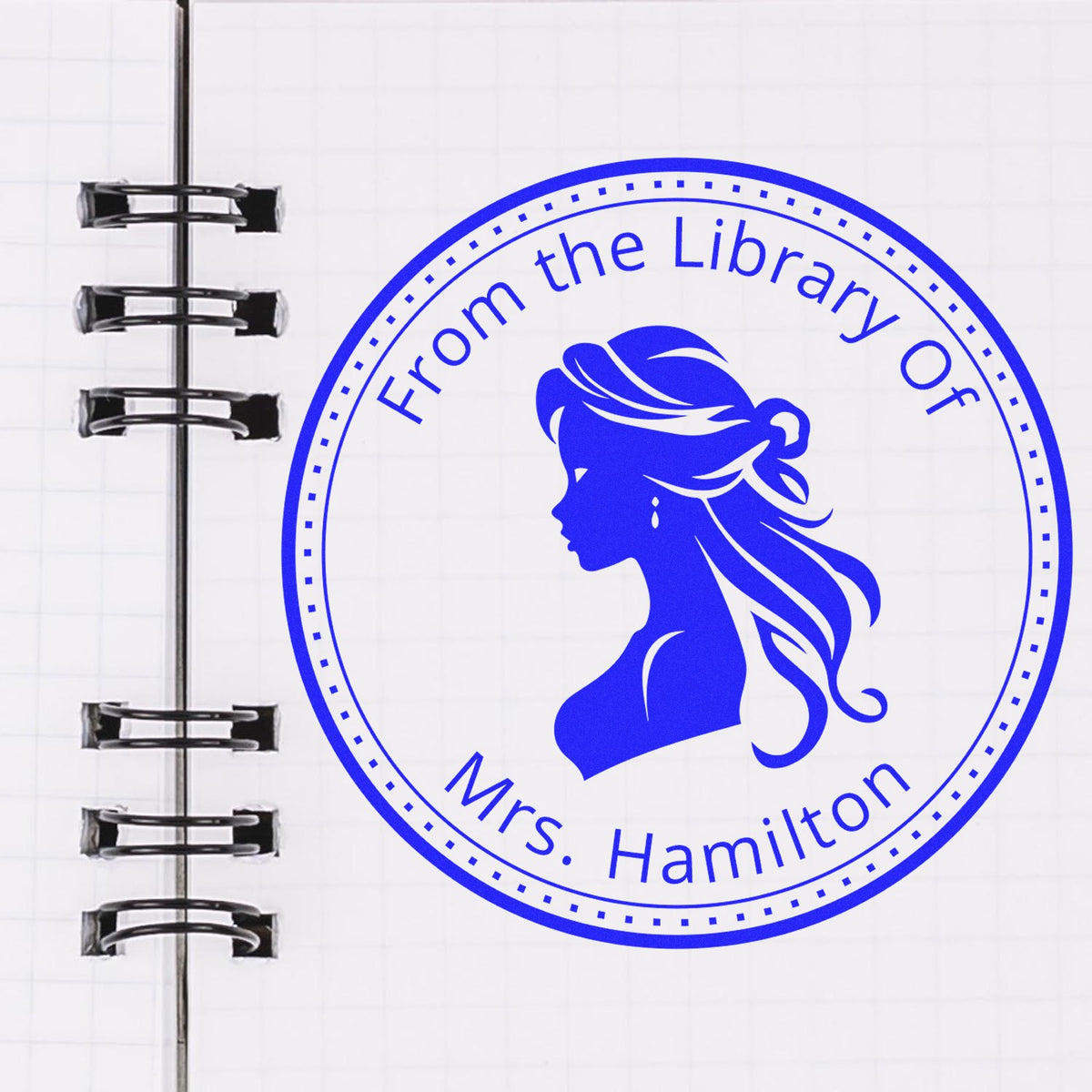 Blue circular library seal stamp on notebook page with female silhouette and text "From the Library of Mrs. Hamilton".