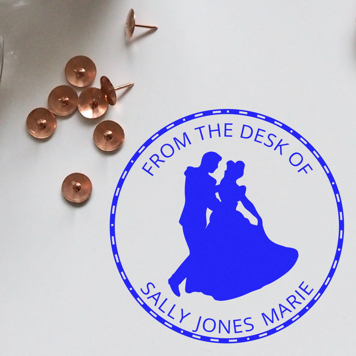 Blue custom desk stamp seal for Sally Jones Marie beside copper seal fasteners on a white background.