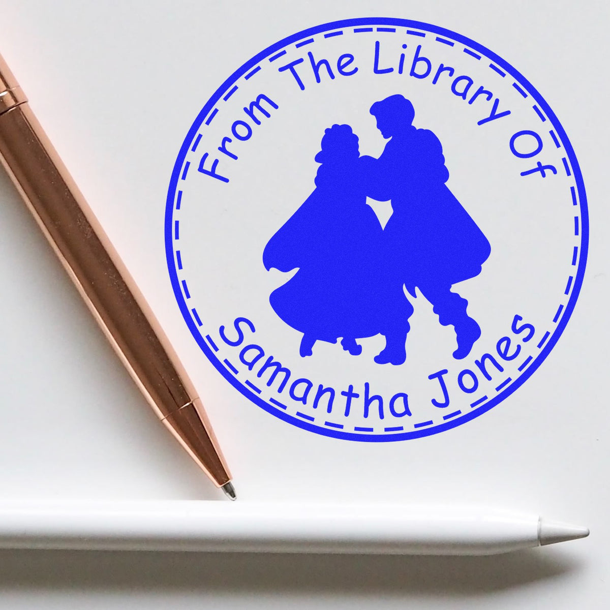 Blue custom library stamp seal reading From The Library Of Samantha Jones with dancing couple silhouette and rose-gold pen.
