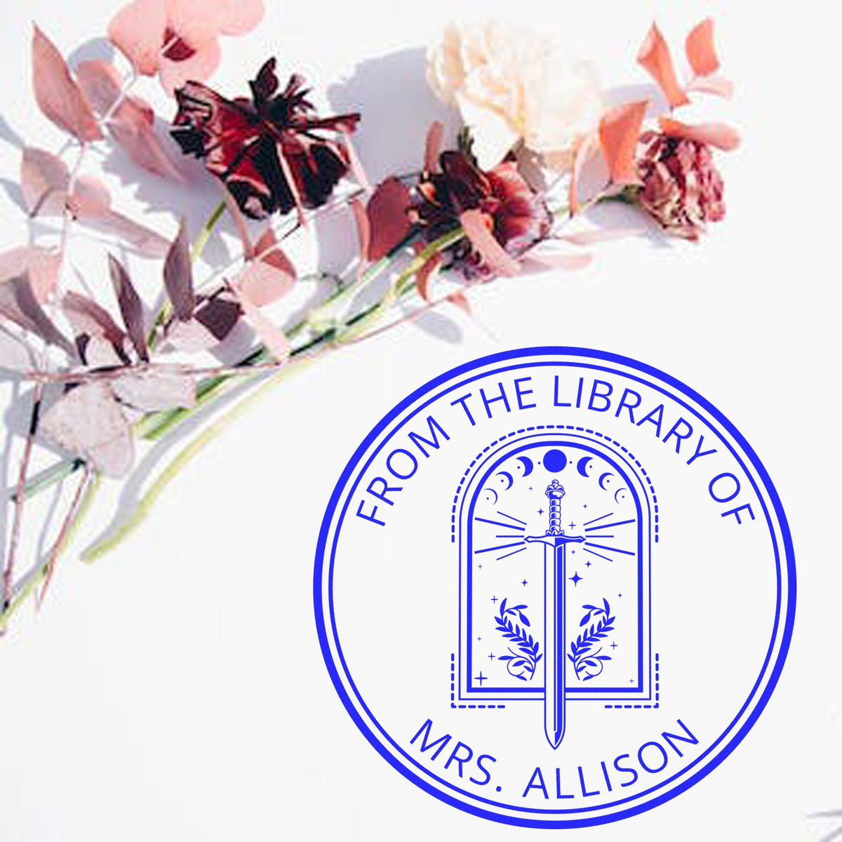 Blue circular library stamp seal with sword emblem, From the Library of Mrs. Allison, beside soft pink flowers.