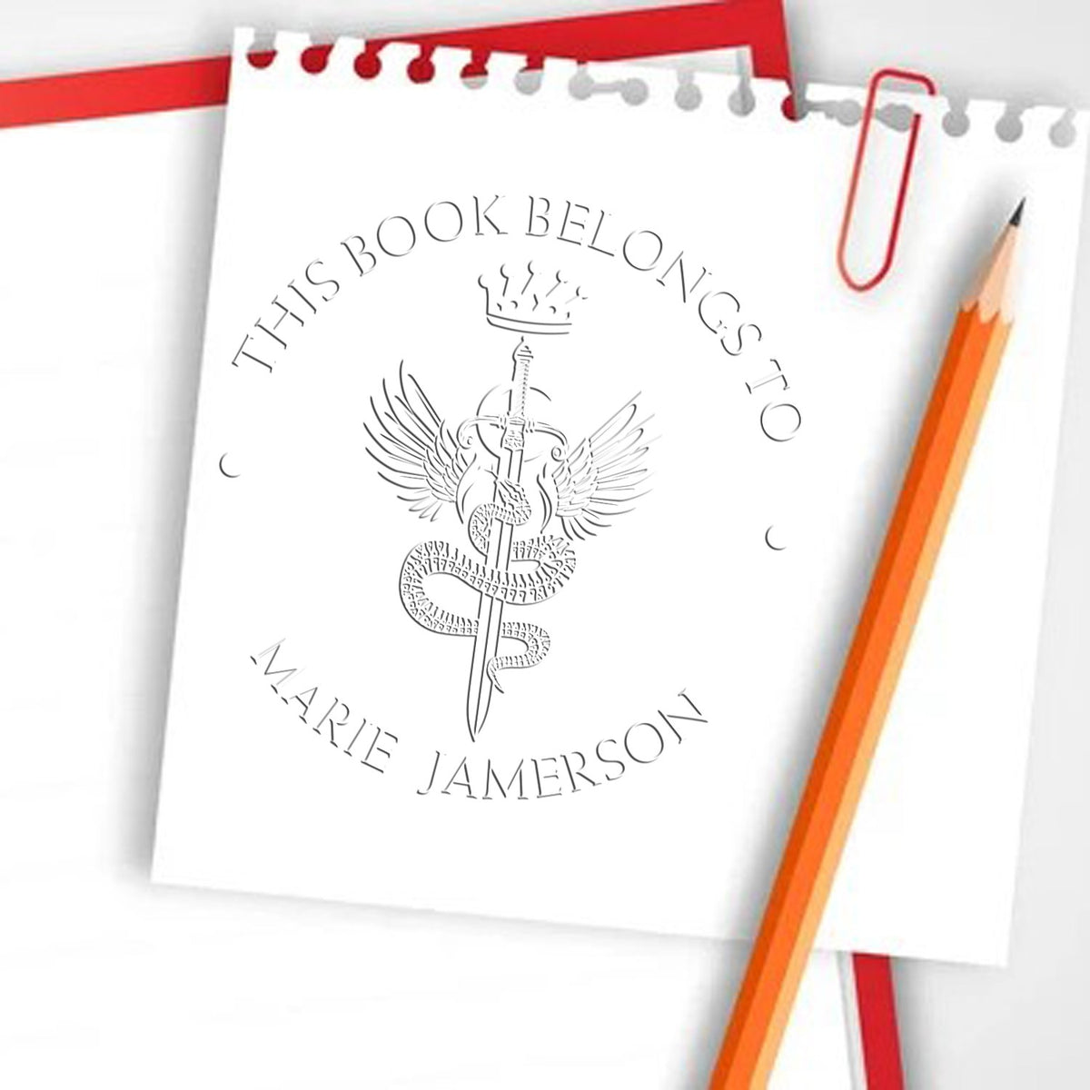 Trodat Starforged Mythical Swords hybrid fantasy stamp in use, featuring detailed sword and library seal design on a stamp pad.