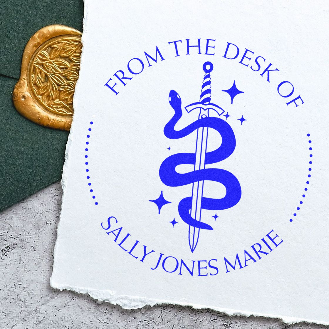 Blue custom desk stamp seal with snake-and-sword logo and Sally Jones Marie text beside a gold wax seal.