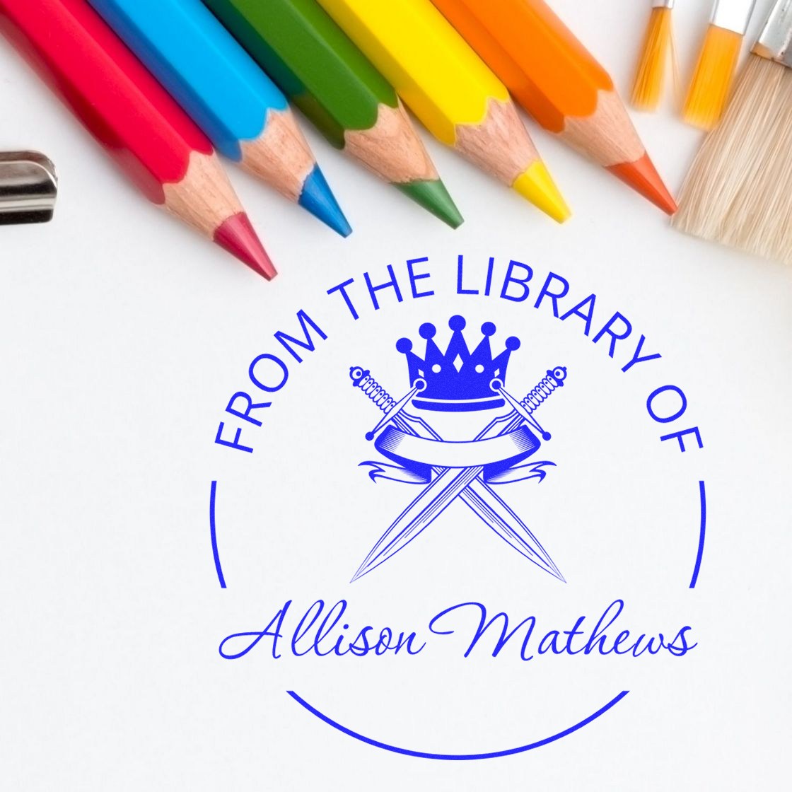 Custom blue library seal stamp with Allison Mathews text, crowned crossed-sword emblem, framed by rainbow colored pencils.