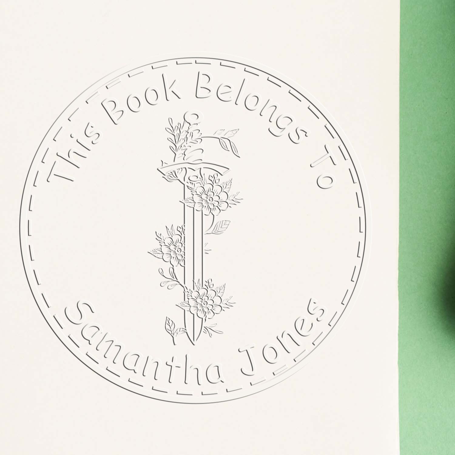 Round white embossed bookplate stamp seal with floral sword emblem and This Book Belongs to Samantha Jones text.