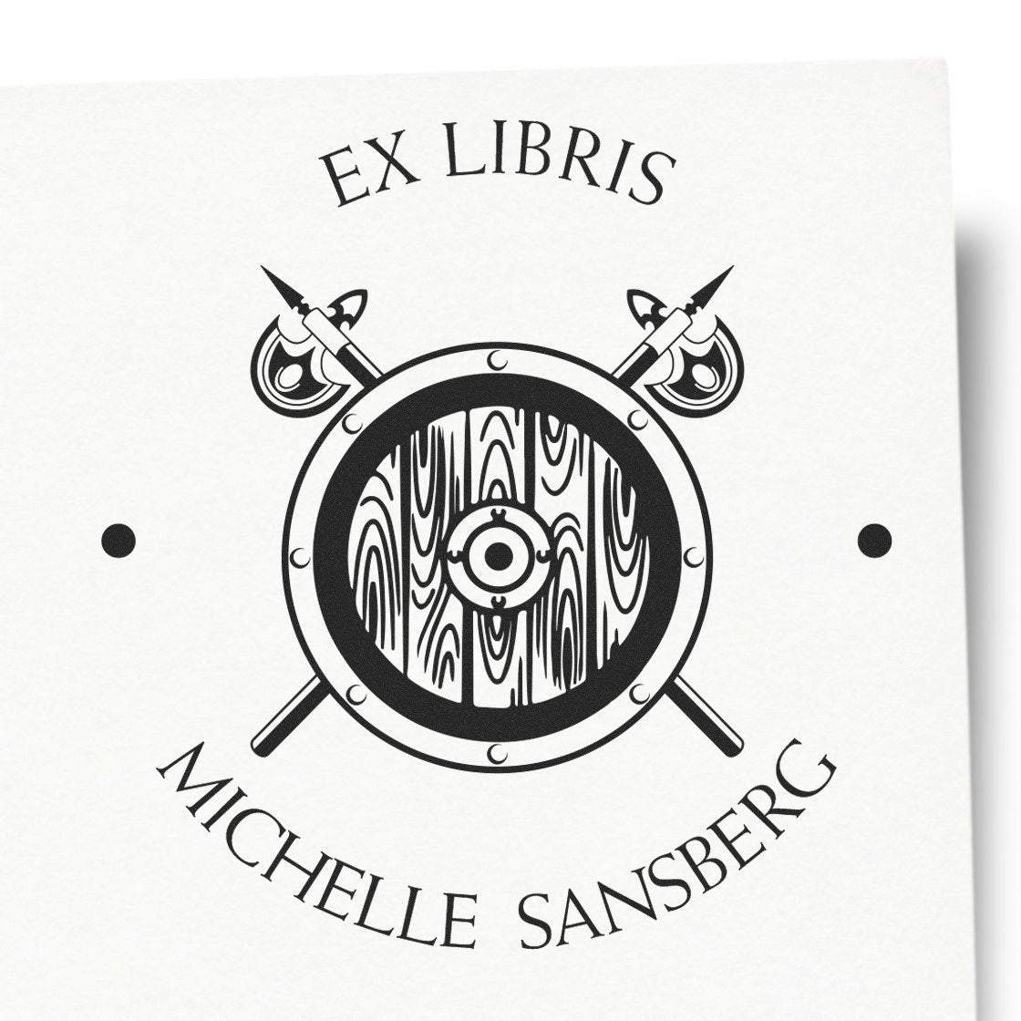 Black-and-white ex libris stamp and seal with circular crest, crossed spears, and Michelle Sansberg text.