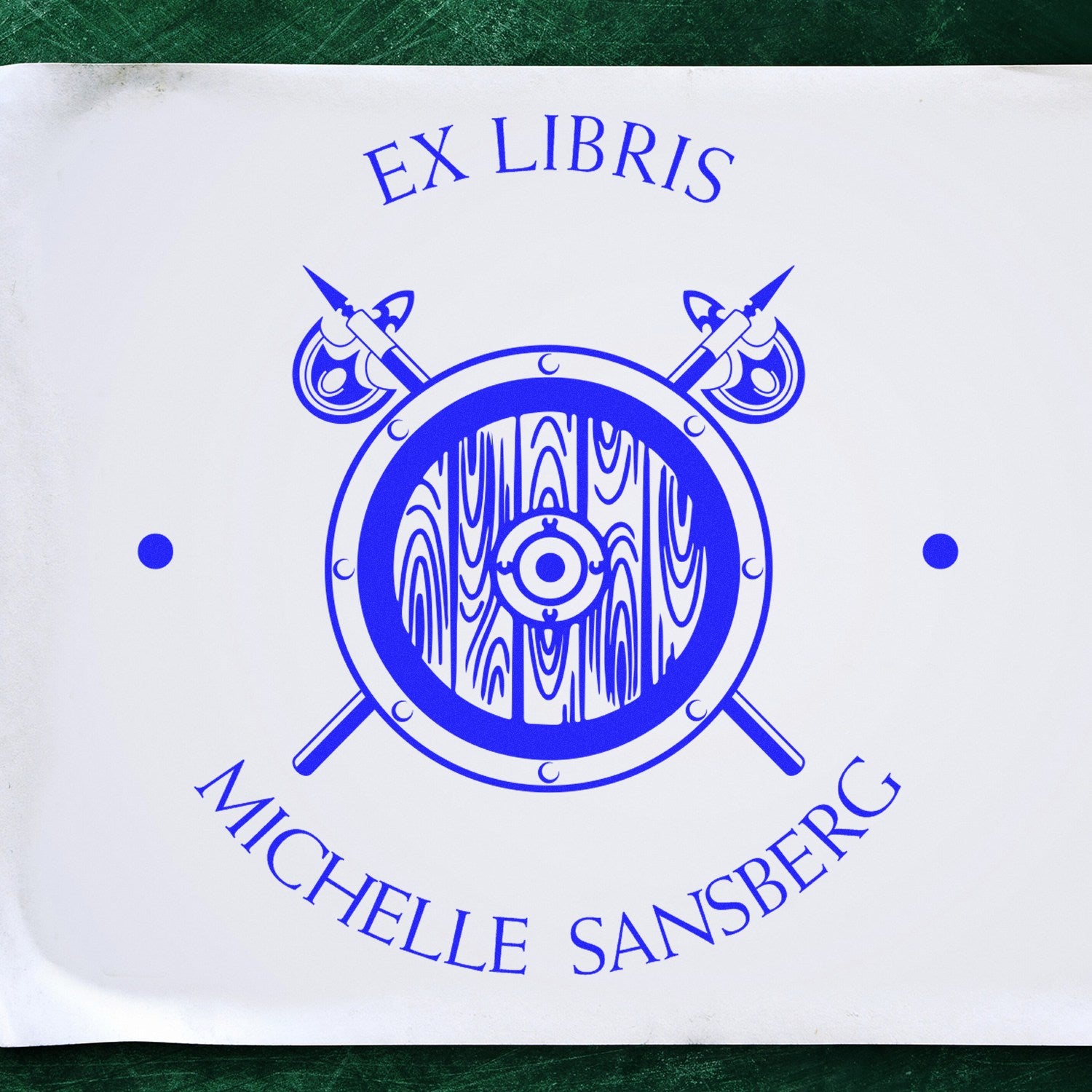 Blue Ex Libris Michelle Sansberg stamp and seal design with crossed spears, circular emblem, and woodgrain center on white