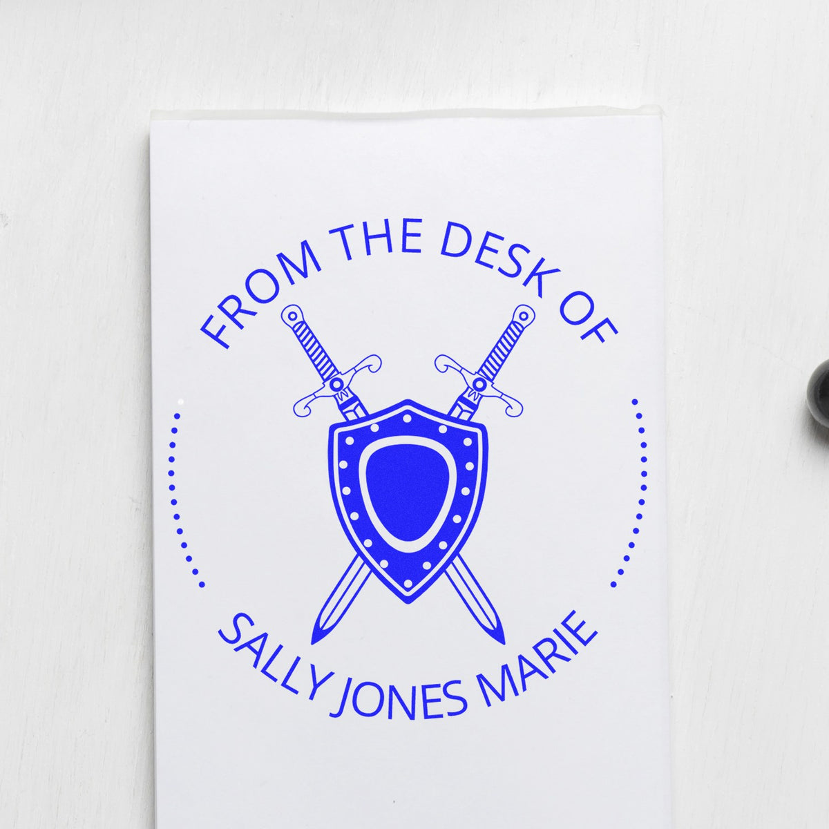 Blue custom stamp and seal design with crossed swords and shield, reading "From the Desk of Sally Jones Marie" on white.