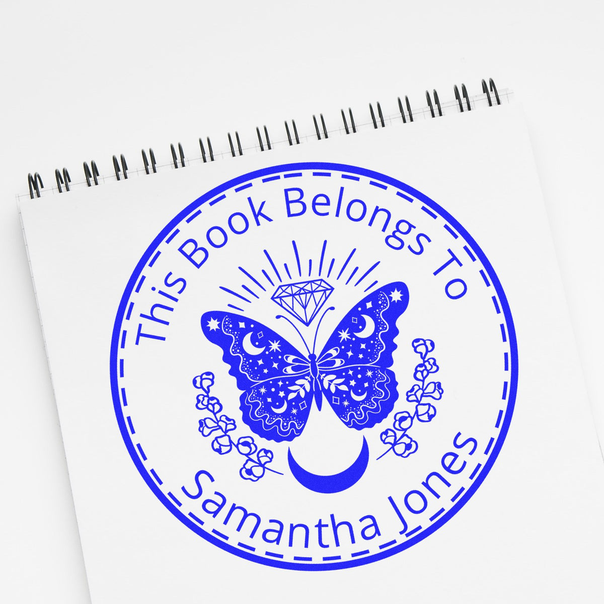 Blue custom book belongs to Samantha Jones stamp seal with butterfly, crescent moon, and floral circular design