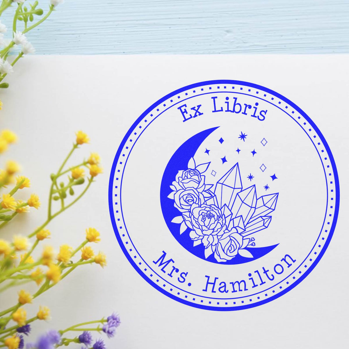 Blue ex libris stamp seal with crescent moon, flowers, crystals, and Mrs. Hamilton on white paper.