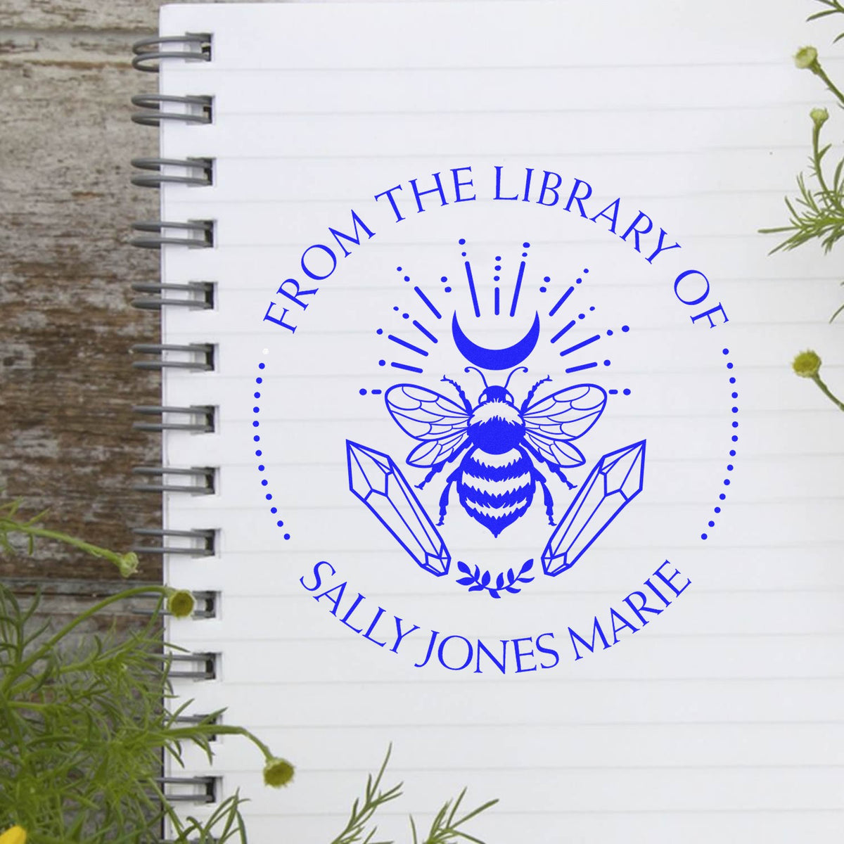 Blue custom stamp and seal with bee, crescent moon and crystals on white notebook page for Sally Jones Marie.