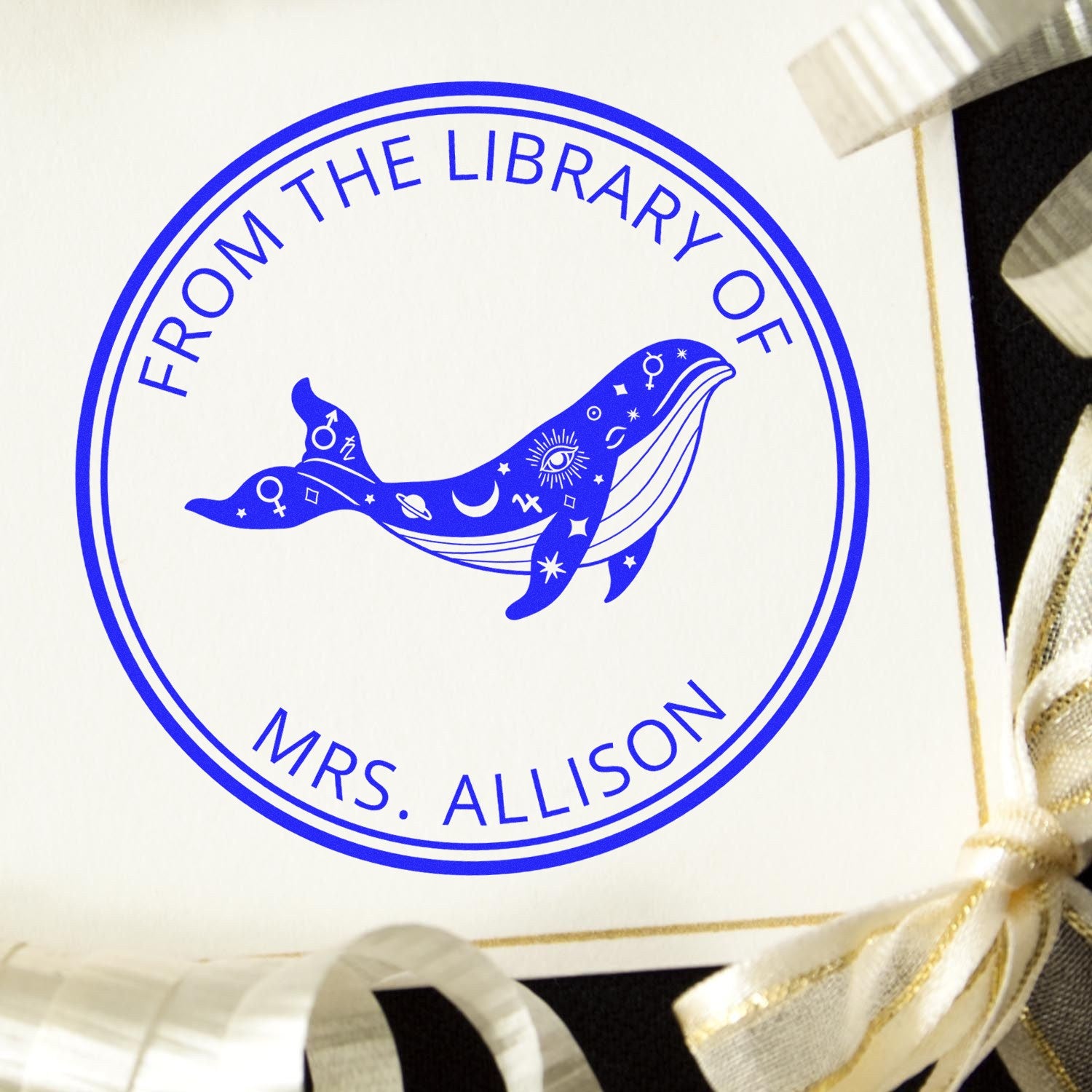 Blue circular library stamp seal with whale and celestial symbols, reading From the Library of Mrs. Allison on white.