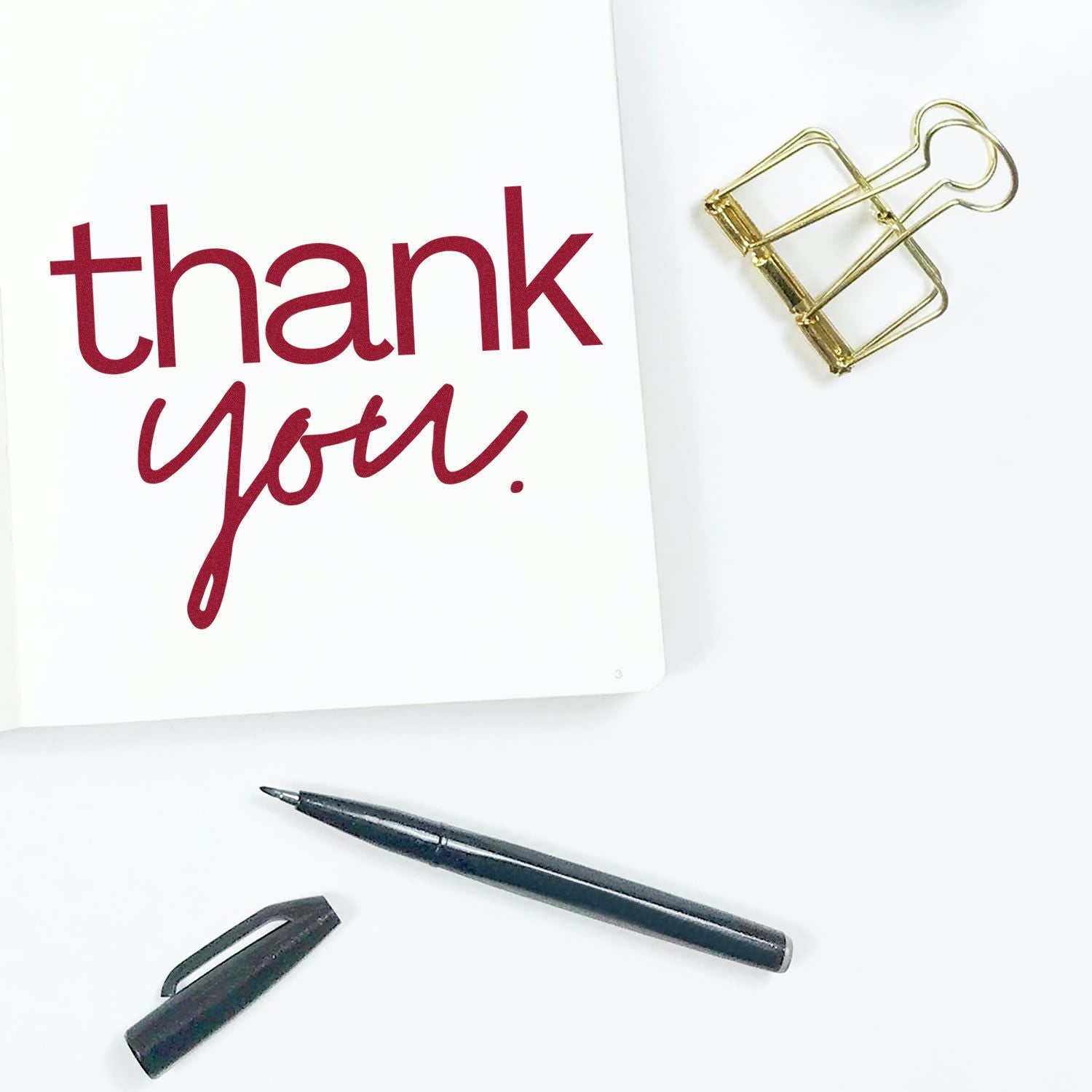 Burgundy thank-you card, gold binder clip, and black pen with cap, styled as stamp and seal stationery products.