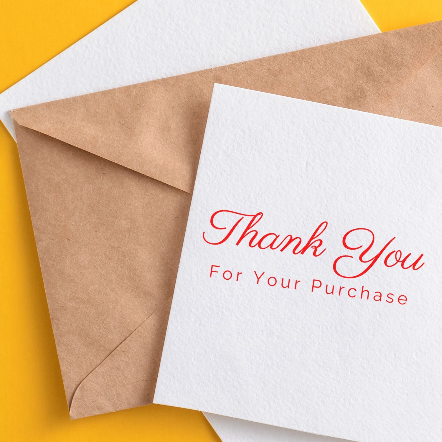 Red thank-you stamp and seal card on white paper with kraft envelope over a yellow background