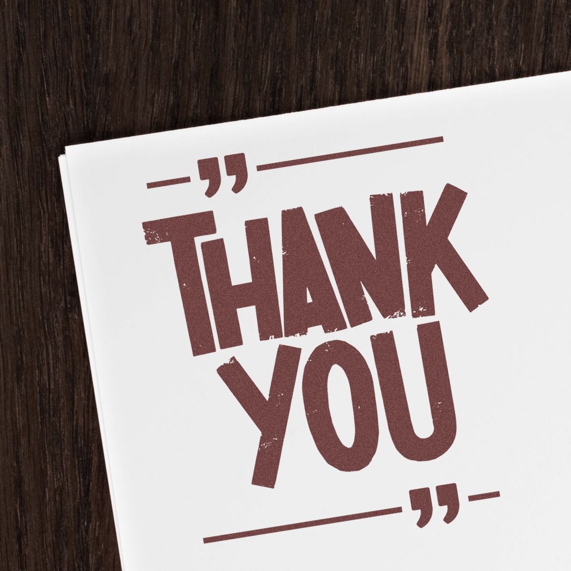 Maroon Thank You stamp and seal design on white card with quote marks, set against a dark wood background.