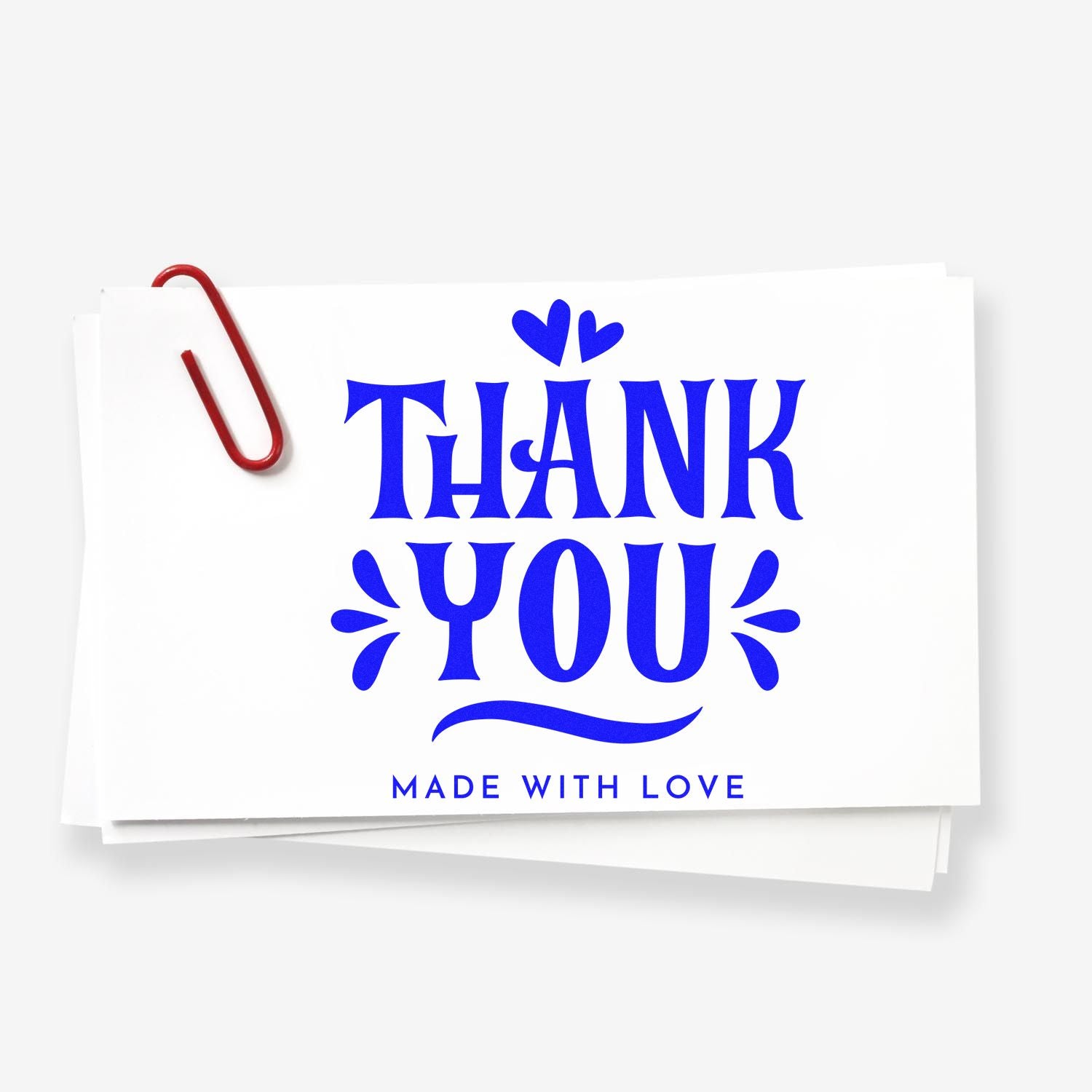 Blue THANK YOU stamp/seal design with hearts and made with love on a white card, clipped with a red paperclip.