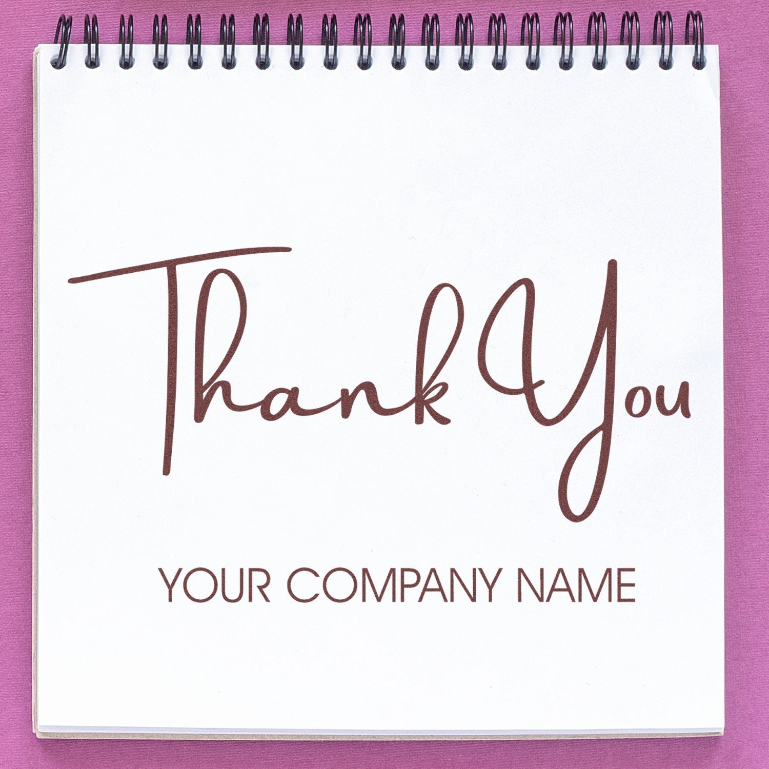 Custom brown thank you stamp and seal on white spiral notebook with company name placeholder, pink background