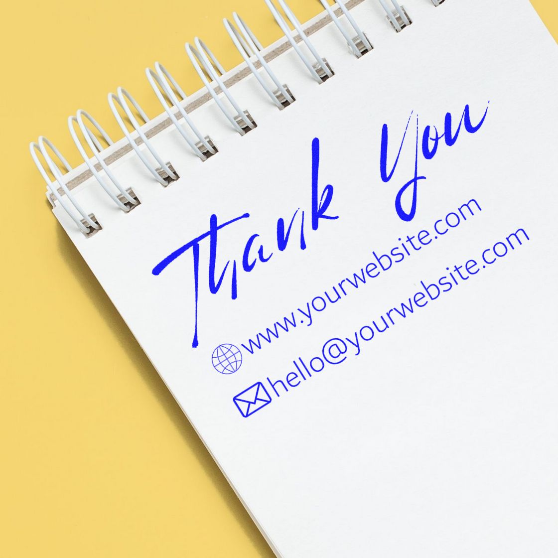 Blue business stamp and seal with Thank You, website, and email on a white spiral notebook over a yellow background.