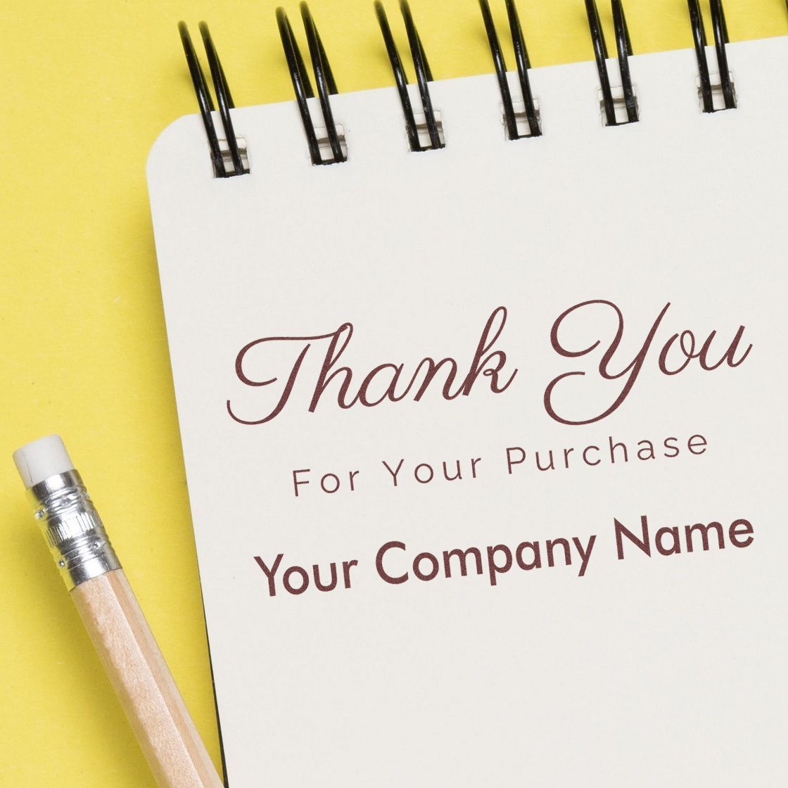 Custom thank-you stamp and seal design on white spiral notebook, with maroon text, yellow background, and pencil.