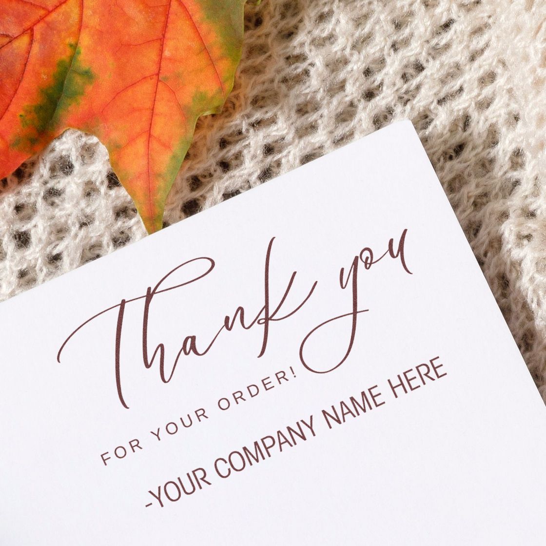 Custom brown thank-you stamp and seal card on beige knit, accented by an orange-green autumn leaf.