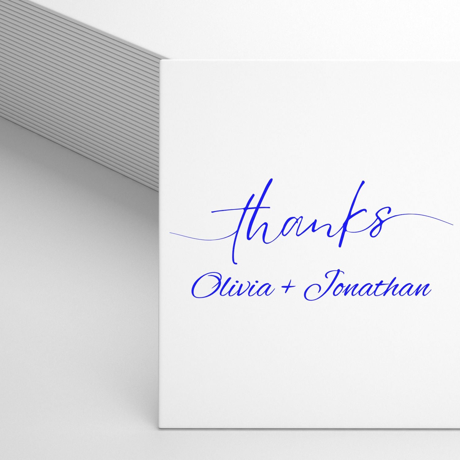 White envelope stamp and seal with blue script thanks and Olivia + Jonathan on a minimalist wedding card.