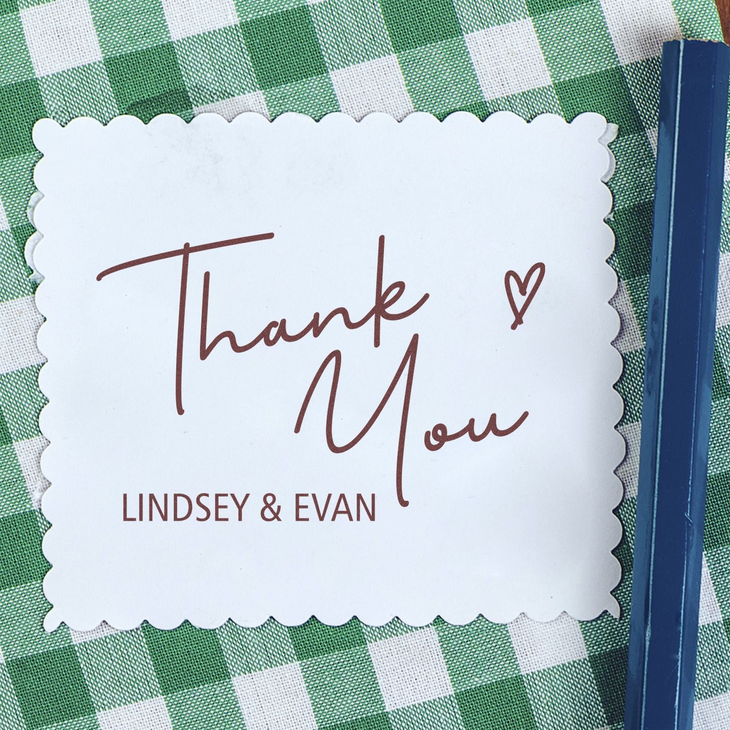 White scalloped thank you stamp seal with brown script and Lindsey & Evan text on a green gingham background.