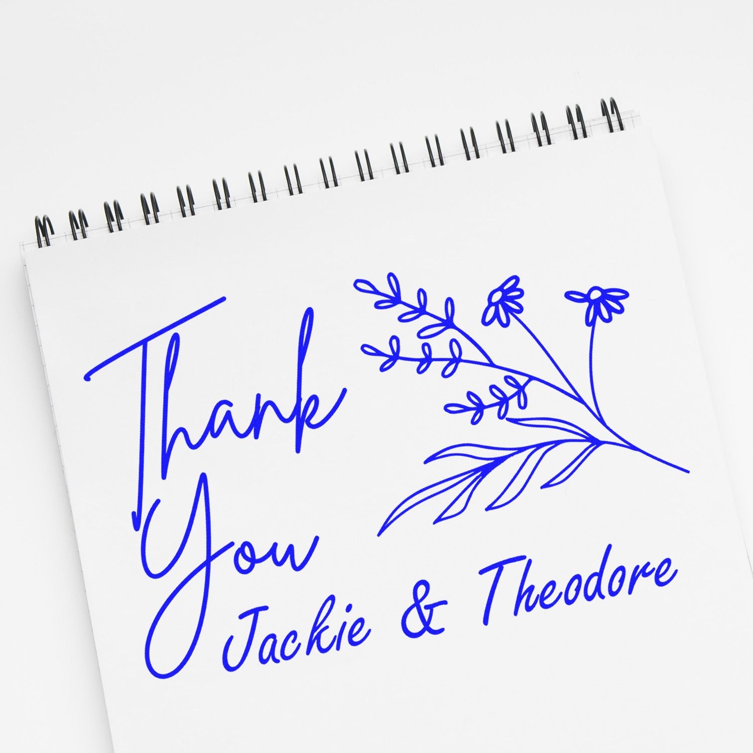 Blue thank you stamp and floral seal on white spiral notebook, personalized for Jackie & Theodore