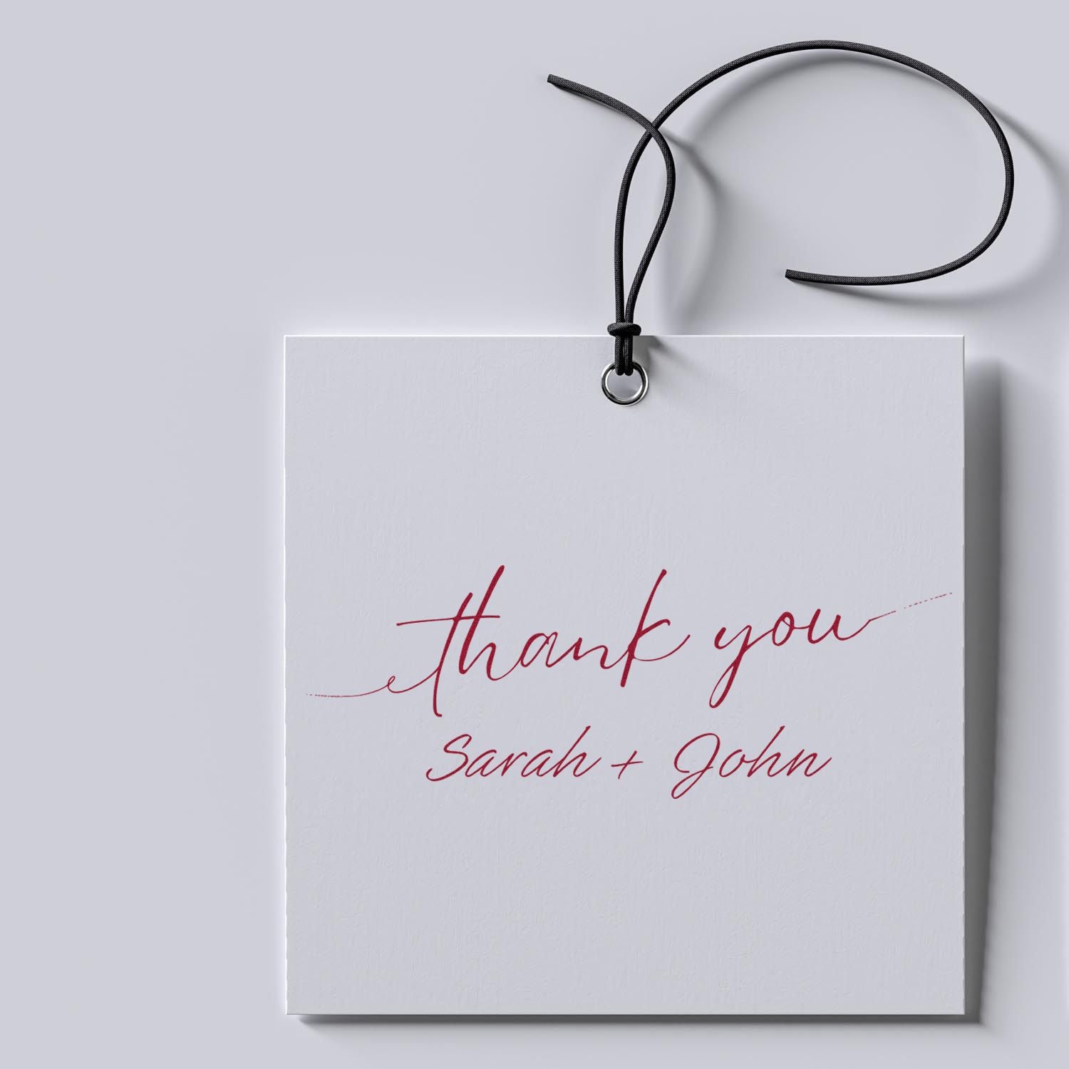White thank-you gift tag with black cord and metal ring, red script thank you and Sarah + John custom stamp and seal