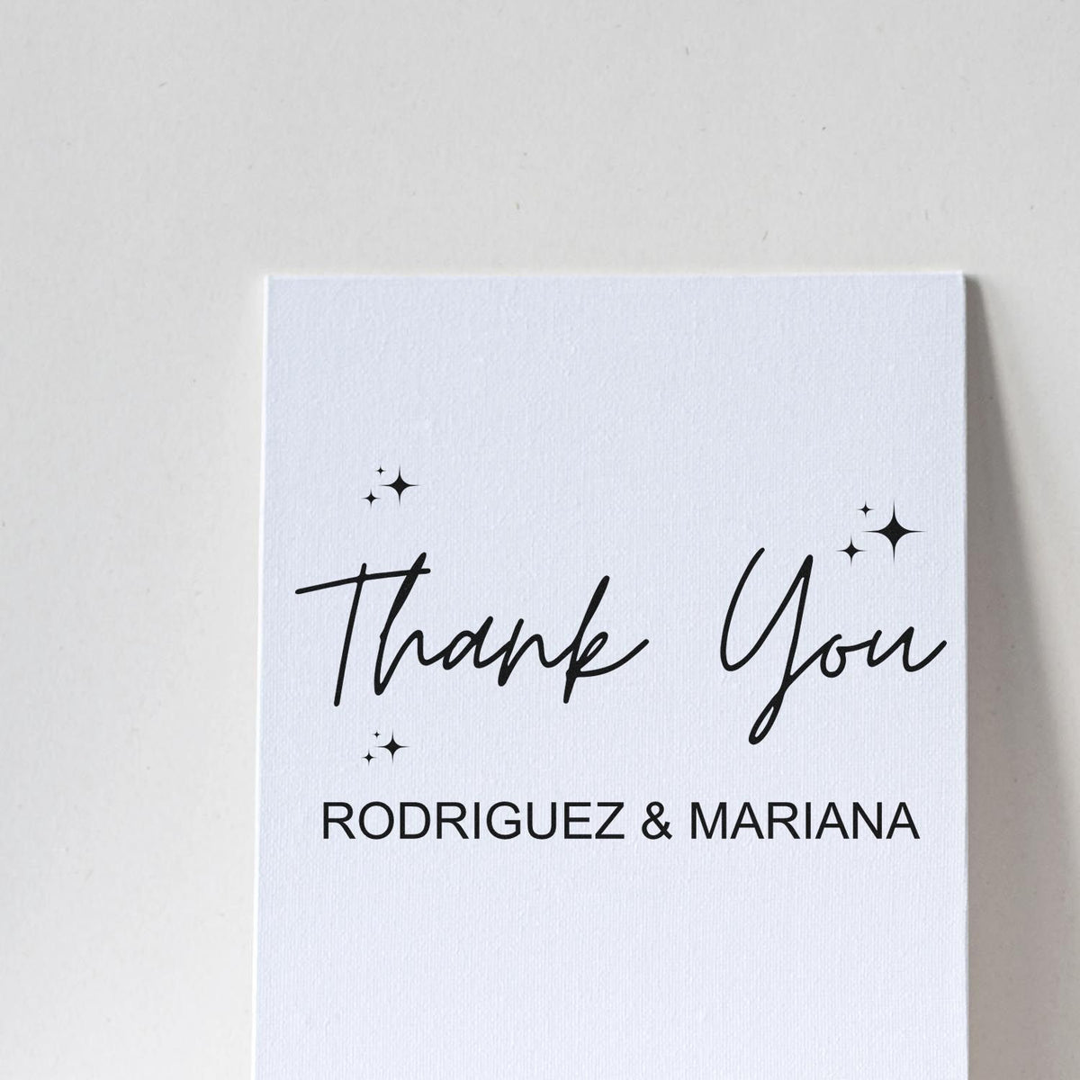White stamp/seal card with black Thank You script, sparkles, and Rodriguez & Mariana text on a white background.
