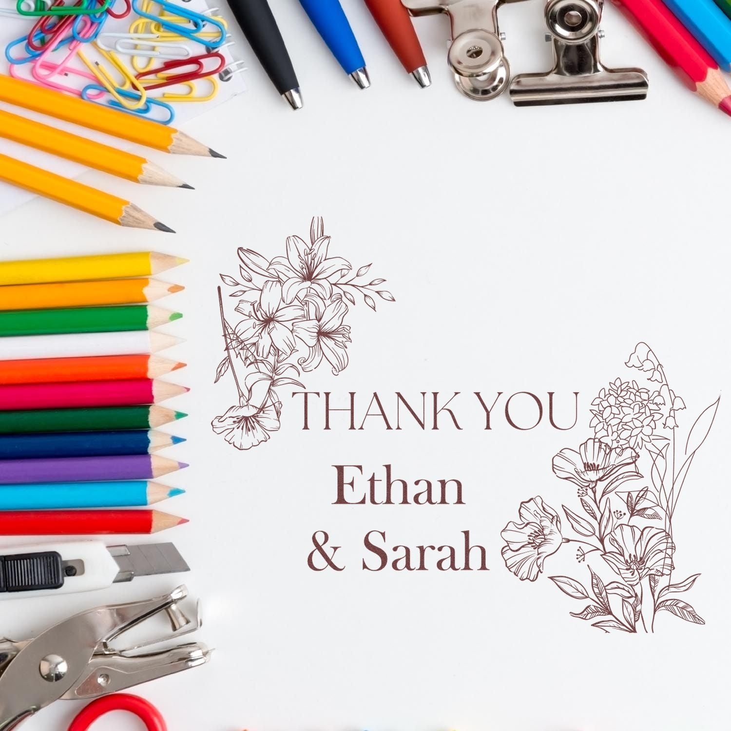 Personalized floral thank-you stamp and seal with Ethan & Sarah, surrounded by colorful pencils, paper clips, and silver tools.