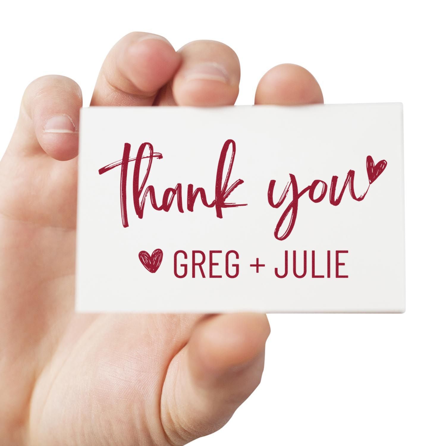 Handheld white custom stamp seal with burgundy Thank you script, heart icon, and Greg + Julie names.