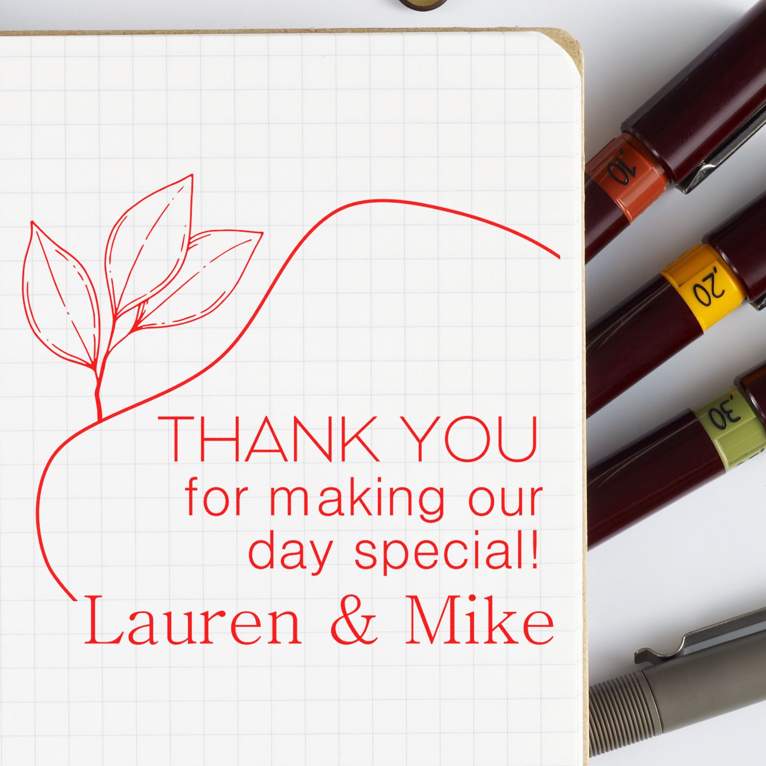 Red thank-you stamp design with leafy heart on grid paper, Lauren & Mike text, and colored stamp and seal tools on the right