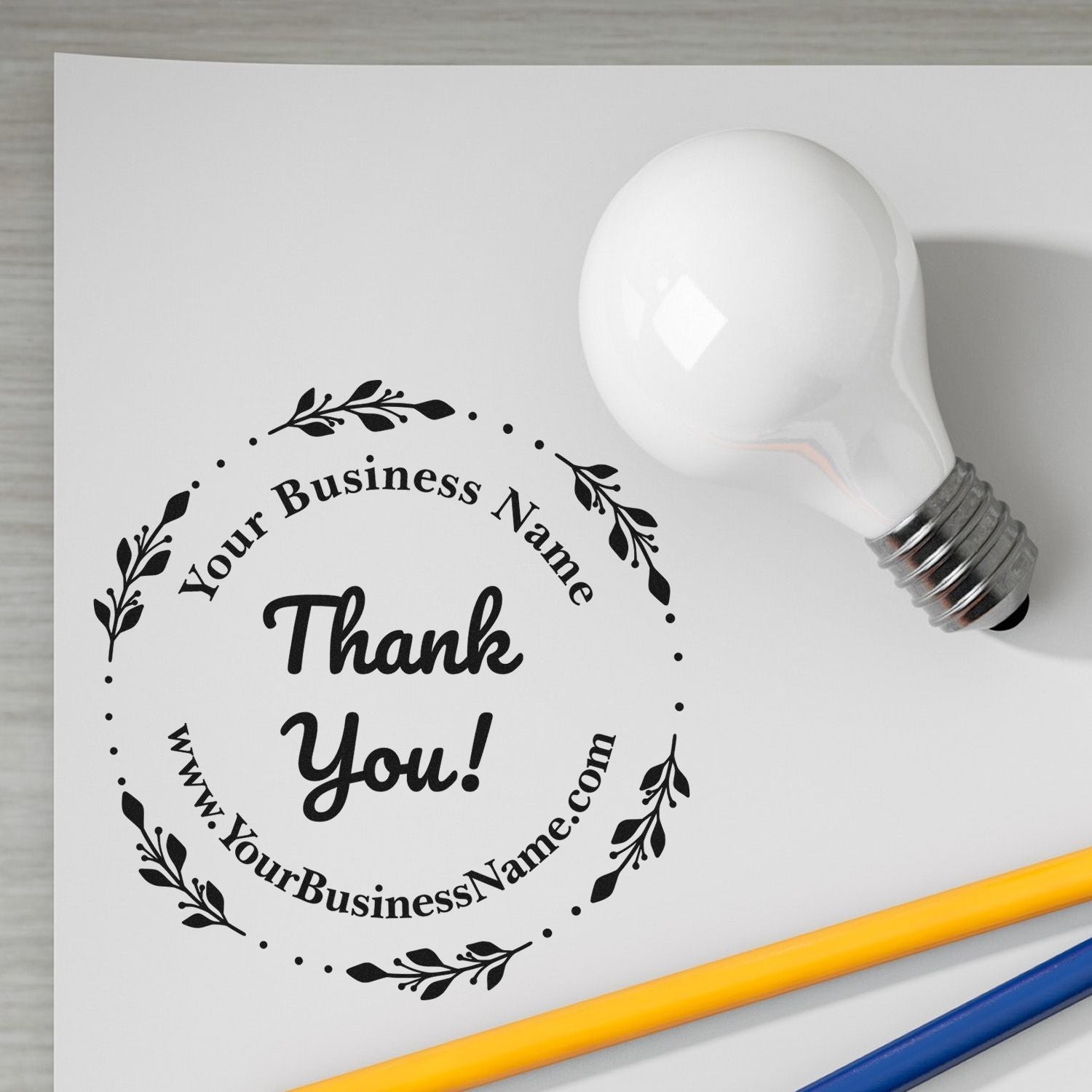 White custom business stamp and seal with black floral Thank You! design on white paper, beside a white bulb-shaped handle.