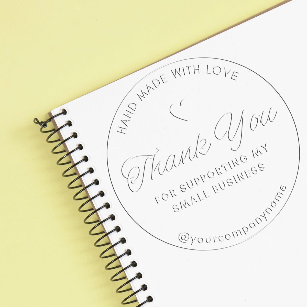 Shiny thank you stamp embossing a heartfelt gratitude message on paper with a circular heart design.