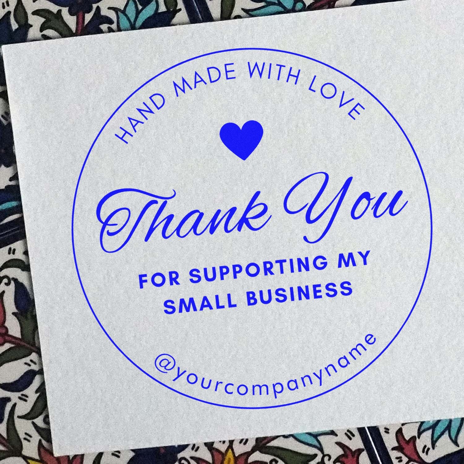 Blue circular thank-you stamp seal with heart, handmade with love and supporting my small business text on white paper.